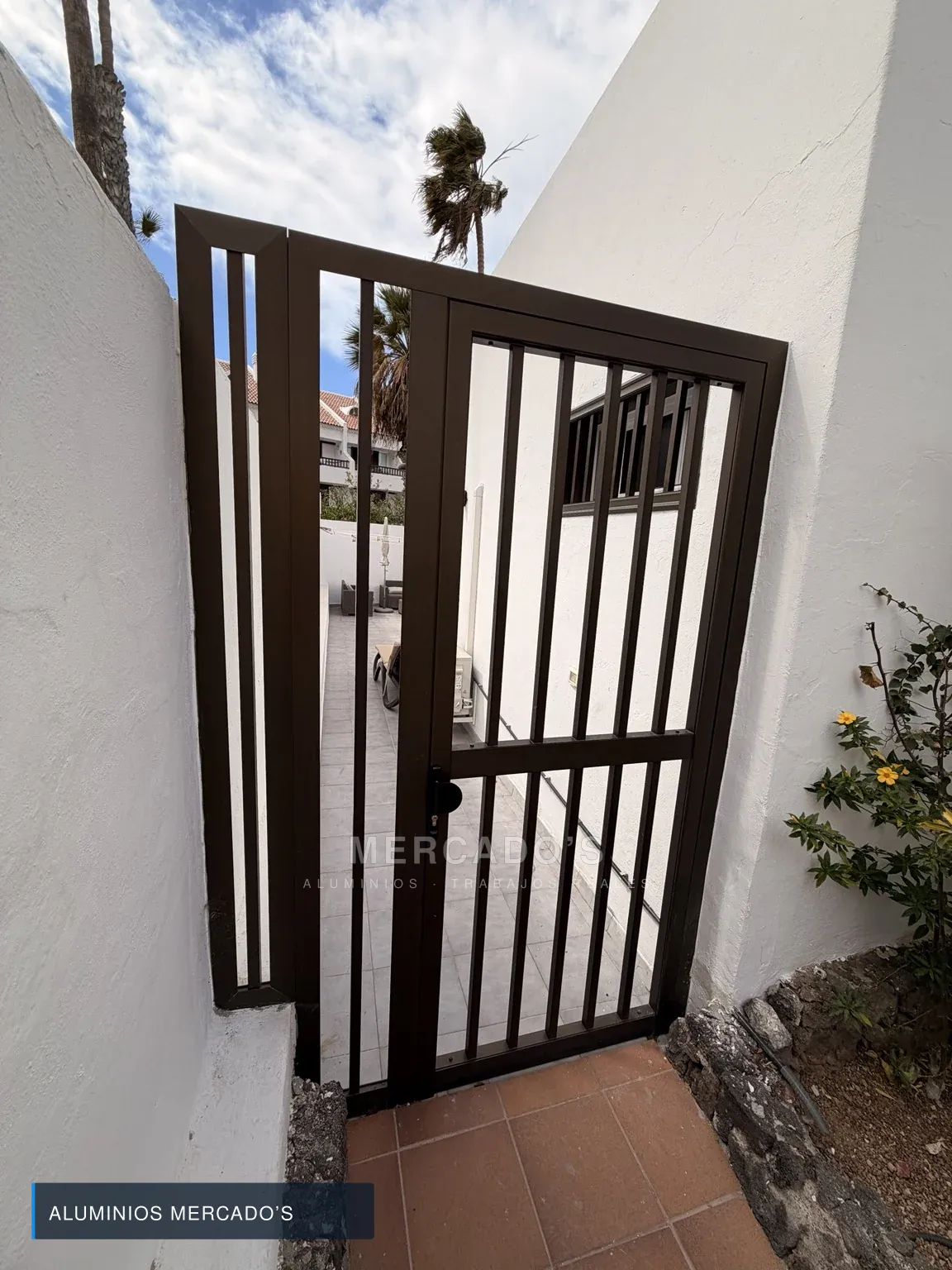 Cancela marrón de barrotes verticales con fijo lateral